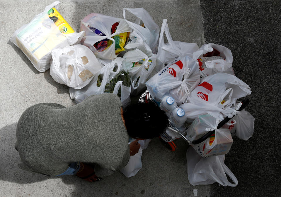 A woman packs her grocery shopping in disposable bags outside a supermarket in Singapore. 