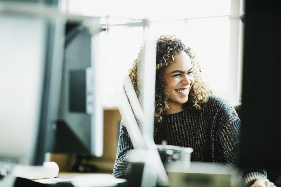 Laughing businesswoman working at workstation in office