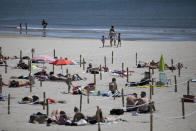 Sunbathers lie in an area marked by cordons of ropes and wooden stakes to enforce social distancing measures in La Grande Motte, southern France, Sunday, May 24, 2020. Grateful French families flocked to the beach at La Grande Motte on the Mediterranean shore Sunday, swimming and sunbathing in areas carefully marked to keep them a safe distance from others. (AP Photo/Daniel Cole)