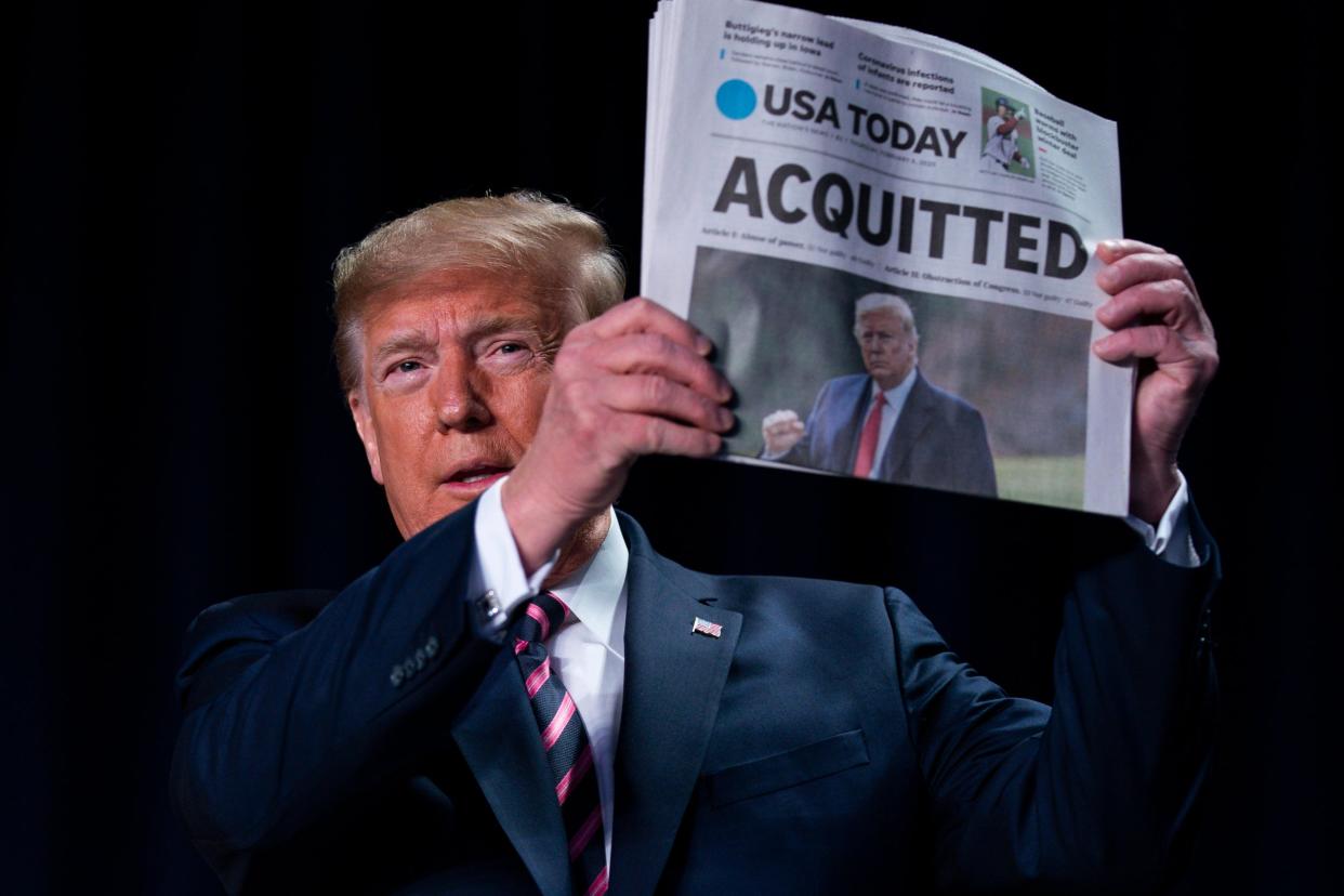 Donald Trump brandishes a newspaper with the banner headline "Acquitted" at the National Prayer Breakfast in Washington, a day after the Senate impeachment trial ended: AP