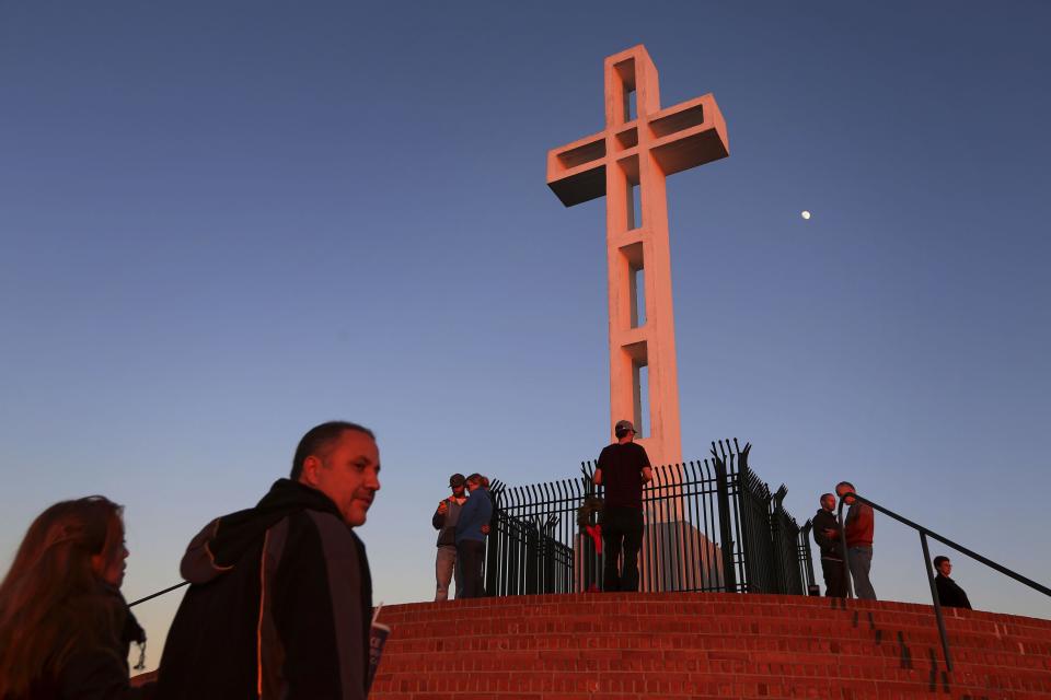 People gather around the massive cross sitting atop the Mt. Soledad War Memorial in La Jolla