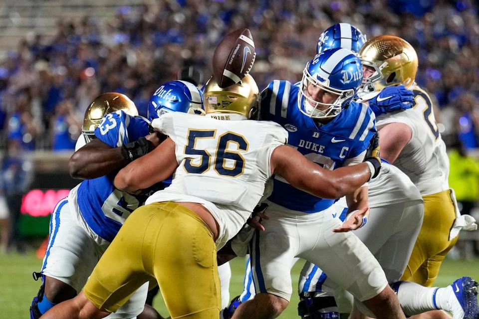 Sep 30, 2023; Durham, North Carolina, USA; Duke Blue Devils quarterback Riley Leonard (13) loses the football near the goal line hit by Notre Dame Fighting Irish defensive lineman Howard Cross III (56) during the second quarter at Wallace Wade Stadium. Mandatory Credit: Jim Dedmon-USA TODAY Sports