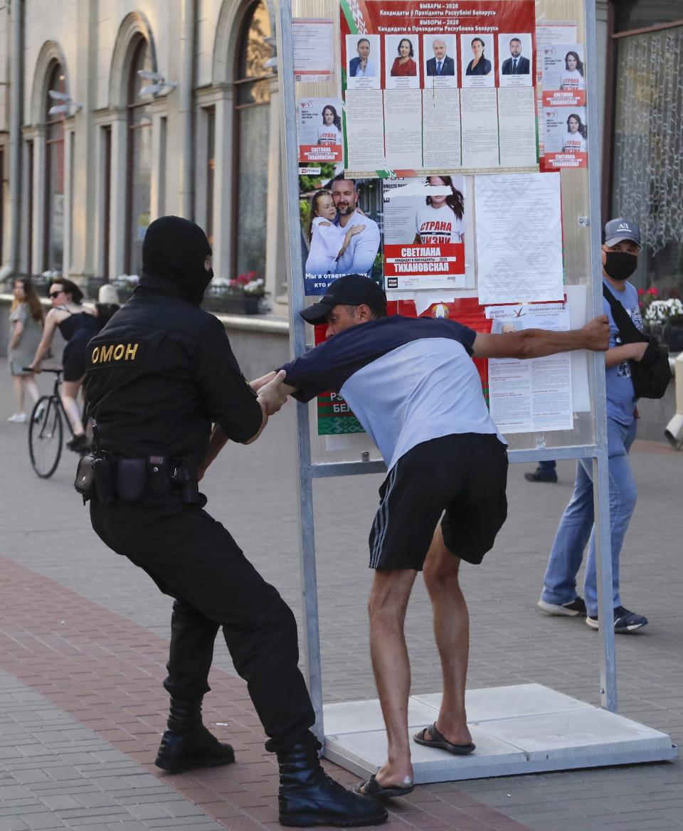 A Belarusian police officer detains a man in Minsk, Belarus, Saturday, Aug. 8, 2020. On Saturday evening, police arrested at least 10 people as hundreds of opposition supporters drove through the center of the capital waving flags and brandishing clenched-fist victory signs from the vehicles' windows. The presidential election in Belarus is scheduled for August 9, 2020. (AP Photo/Sergei Grits)