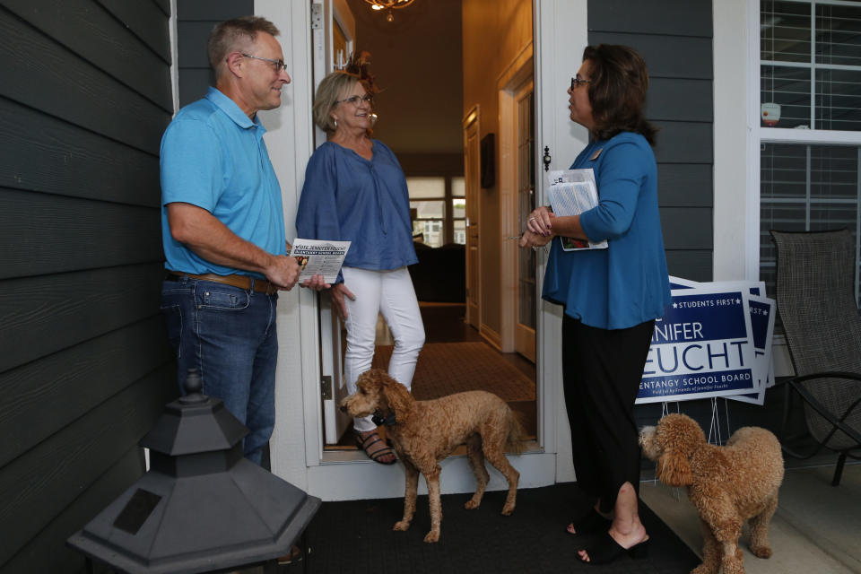 Jennifer Feucht, right, candidate for Olentangy Local Board of Education, delivers campaign flyers and yard signs to Brad, left, and Tina Krider Thursday, Oct. 7, 2021, in Westerville, Ohio. Across Ohio and the nation, parental protests over social issues like mask mandates, gender-neutral bathrooms, teachings on racial history, sexuality and mental and emotional health are being leveraged into school board takeover campaigns. (AP Photo/Jay LaPrete)