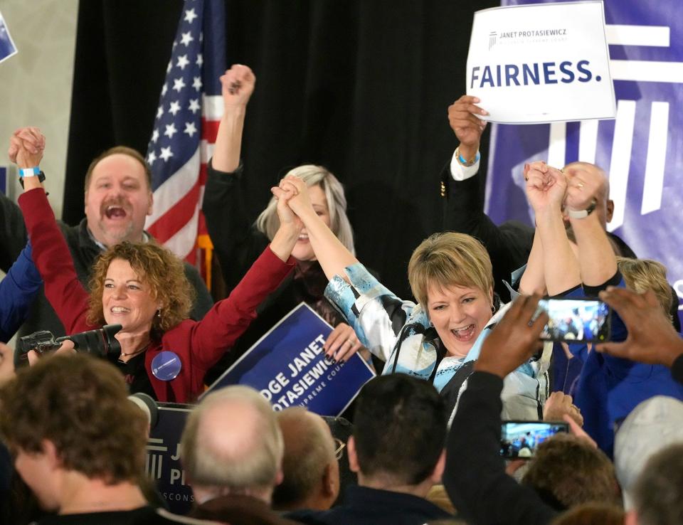 Supreme Court candidate Janet Protasiewicz (center) holds hands with Wisconsin Supreme Court Justice Rebecca Dallet (far left) and Wisconsin Supreme Court Justice Ann Walsh Bradley (right of Protasiewicz) Tuesday night at Saint Kate - The Arts Hotel in Milwaukee to celebrate her election night victory over Dan Kelly.