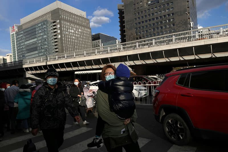 Woman carrying a child walks outside a children's hospital in Beijing