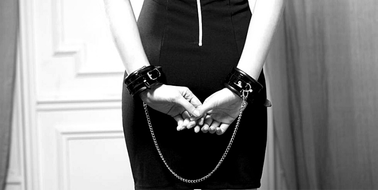 woman with handcuffs behind back wearing black dress