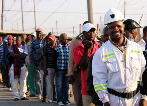 Thousands of Lonmin miners wait in line as they resume work in Marikana after ending a deadly six-week wildcat strike. South African police clashed with residents near an Anglo American mine on Thursday, as miners at nearby Lonmin went back to work