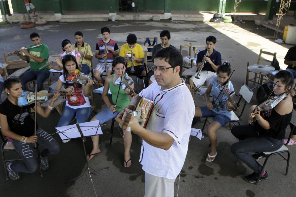 In this Dec. 11, 2012 photo, Music Director Fabio Chavez leads his students from "The Orchestra of Instruments Recycled From Cateura" in a practice session in Cateura, a vast landfill outside Paraguay's capital of Asuncion, Paraguay. Chavez had learned clarinet and guitar as a child, and had started a small music school in another town in Paraguay before he got a job with an environmental organization teaching trash-pickers in Cateura how to protect themselves. Chavez opened a tiny music school at the landfill hoping to keep youngsters out of trouble. But he had just five instruments to share. (AP Photo/Jorge Saenz)