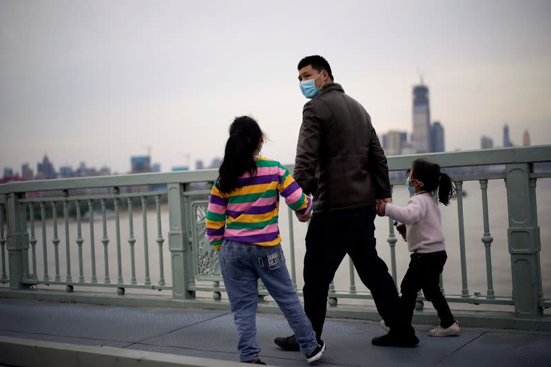 People wearing face masks walk on a bridge in Wuhan