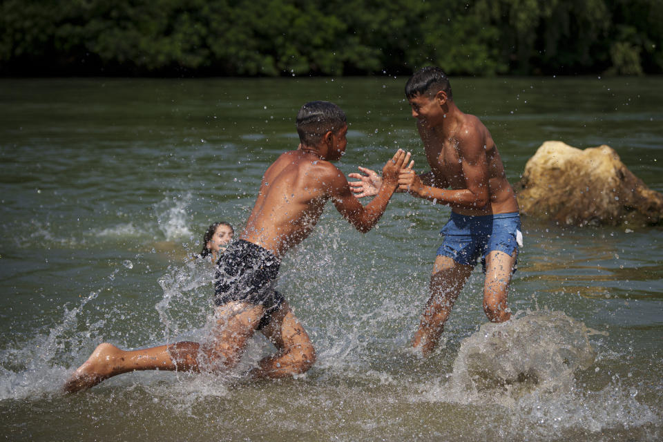 Youngsters cool off in the river Arges, outside Bucharest, Romania, Wednesday, July 12, 2023. Weather services issued a heat warning for the coming days in southern Romania, with temperatures expected to exceed 40 degrees Centigrade (104 Fahrenheit) in the shade. (AP Photo/Andreea Alexandru)