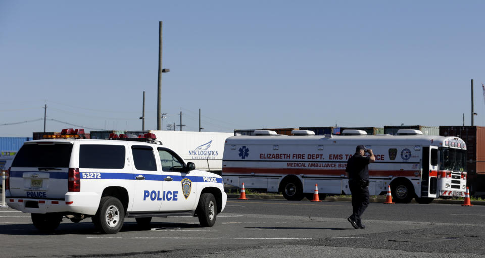 A police official stands near the entrance to a terminal at Port Newark, Wednesday, June 27, 2012, in Newark, N.J. The Coast Guard suspects there are stowaways in a container that was loaded on a ship. Coast Guard spokesman Charles Rowe says a boarding party heard sounds consistent with people coming from the container. The container was loaded aboard The Villa D'Aquarius in India. The manifest says the container was carrying machine parts to be unloaded in Norfolk, Va. (AP Photo/Julio Cortez)