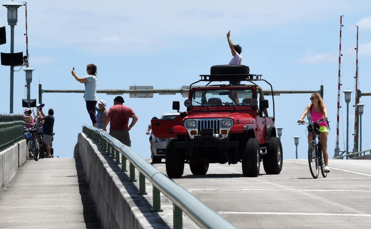 People waive to the boats below the Donald Ross Road bridge in Jupiter as hundreds of Trump supporters take to the Intracoastal Waterway in a show of support during a boat parade from Jupiter to Mar-a-Lago in Palm Beach. Sunday, May 3, 2020 in West Palm Beach.