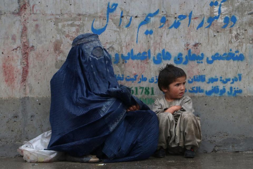 An Afghan woman and a child sits along a path, after a drizzle in Fayzabad district of Badakhshan province (AFP via Getty Images)