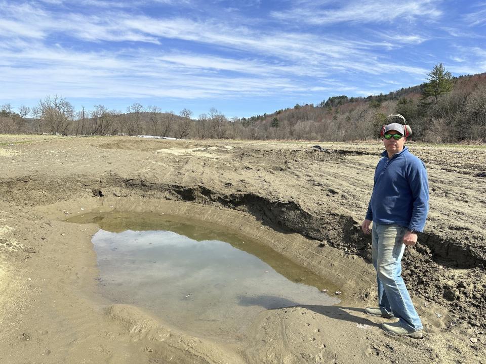 Farmer George Gross, of Dog River Farm in Berlin, Vt., stands, Wednesday, April 17, 2024, next to a hole left in his field by December, 2023, flooding. The farm lost nearly all of its produce in the catastrophic summer flooding that hit Vermont in July. (AP Photo/Lisa Rathke)