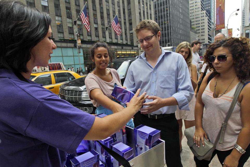 This Wednesday, Aug. 8 2012 photo shows Diana Hunter, left, handing out free vibrators by Trojan to Simon Reed, center, during a promotional giveaway in New York. While Trojan has been selling vibrators since 2009, first-quarter sales this year, around the time the "Fifty Shades of Grey" books hit it big, were up about 14 percent from the same quarter a year before, according to Nielsen. (AP Photo/Mary Altaffer)