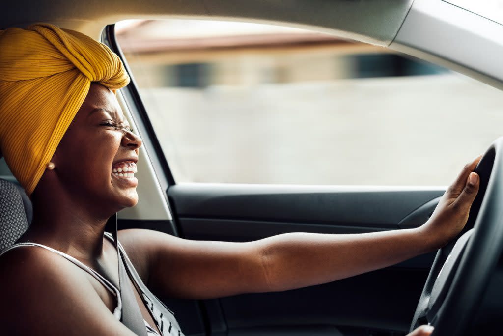 A woman laughs as she drives her car.