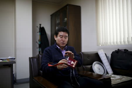 Seo Jae-pyoung, the secretary general of the association of the North Korean defectors, looks at a Workers' Party membership card holder while demonstrating the use of it during an interview with Reuters in Seoul, South Korea, April 22, 2016. REUTERS/Kim Hong-Ji