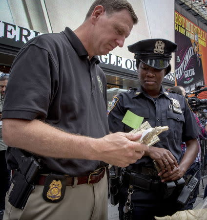 A Department of Interior Special Agent and a New York City NYPD officer examine a piece of confiscated ivory that is to be crushed in New York's Times Square June 19, 2015. REUTERS/Brendan McDermid