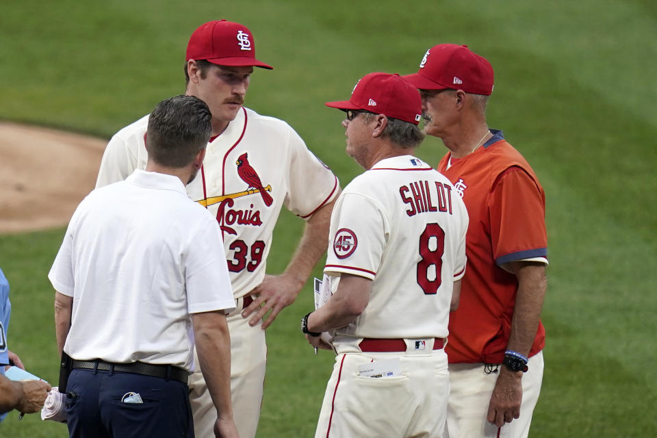 St. Louis Cardinals starting pitcher Miles Mikolas (39) talks with manager Mike Shildt (8) as pitching coach Mike Maddux, right, and trainer Adam Olsen, left, listen before the start of the fifth inning of a baseball game against the Chicago Cubs Saturday, May 22, 2021, in St. Louis. Mikolas walked off the field before warming up for the inning. (AP Photo/Jeff Roberson)
