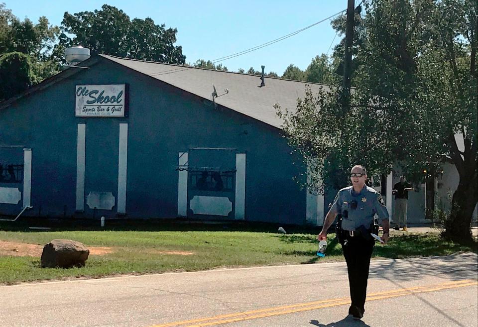 A Lancaster County Sheriff's deputy walks around the Old Skool Sports Bar and Grill, the scene of a shooting early in the morning, north of Lancaster, S.C. on Sept. 21, 2019.  Lancaster County Sherriff's Office said in a statement that the agency was investigating a fatal shooting that also injured several people.