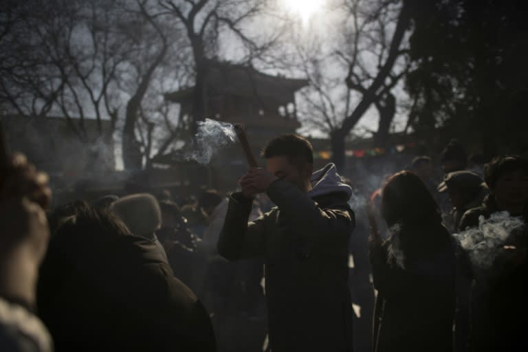 A man prays with incense sticks to celebrate the Lunar New Year, which has had an unusually subdued start in Beijing