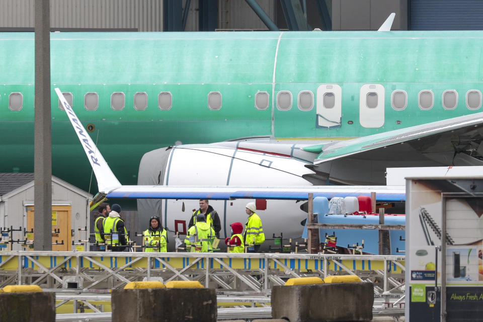 Workers are pictured next to an unpainted 737 aircraft and unattached wing with the Ryanair logo as Boeing's 737 factory teams hold the first day of a 