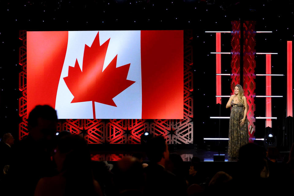 blake giving the speech on stage with a canadian flag on the screen