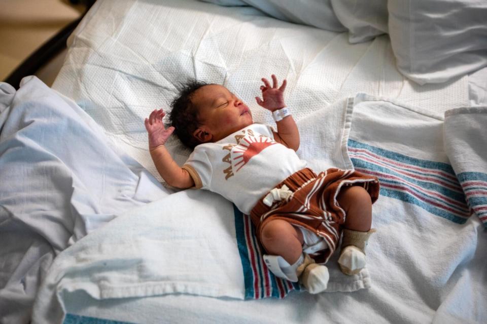 A baby lies on a hospital bed.