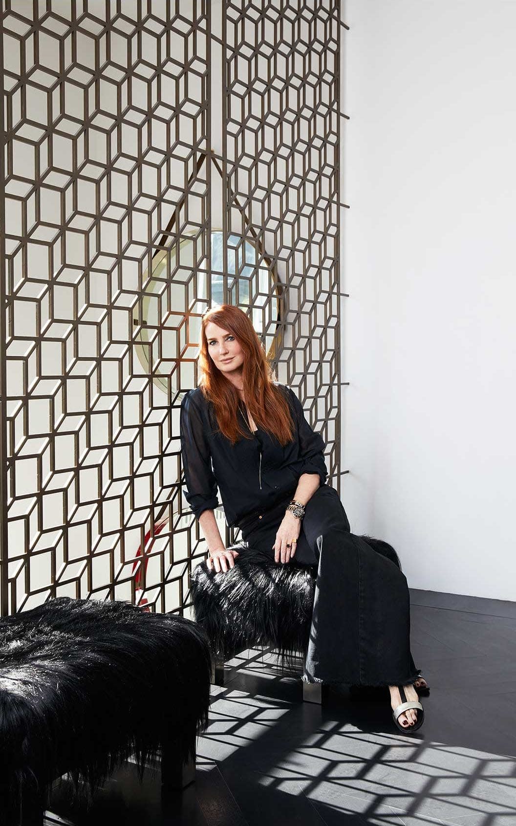 Angela sits on one of a pair of 1970s Mongolian goatskin stools by Paul Evans; the bronze-finished decorative screens were designed by her husband Colin Radcliffe (colinradcliffe.com) - Kate Martin