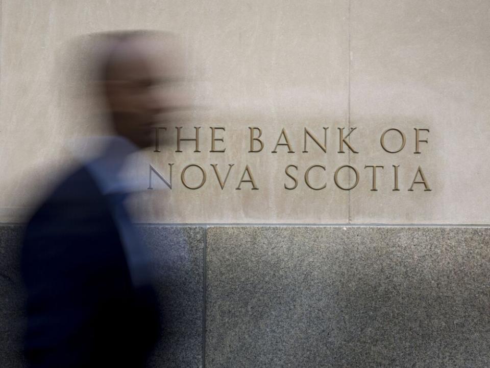  A commuter walks past signage displayed on the Bank of Nova Scotia in Toronto.