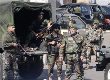 Lebanese army soldiers stand near a booby-trapped car (black, in background) loaded with explosives in the Corniche al-Mazraa district of central Beirut February 12, 2014. REUTERS/Mohamed Azakir