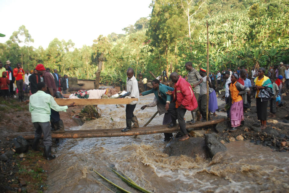 Residence carry an injured person over a river filled with mud in Bududa District, Uganda, Friday, Oct. 12, 2018. At least 30 people died in mudslides triggered by torrential rains in a mountainous area of eastern Uganda that is prone to such disasters, a Red Cross official said Friday. More victims were likely to be discovered when rescue teams access all the affected areas in the foothills of Mount Elgon, said Red Cross spokeswoman Irene Nakasiita. (AP Photo/ Ronald Kabuubi)