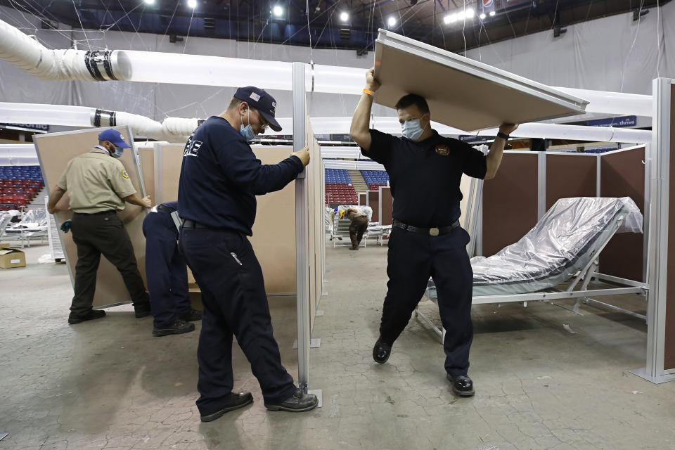 FILE - In this April 18, 2020, file photo, partitions are installed between beds as Sleep Train Arena is turned into a 400-bed emergency field hospital to help deal with the coronavirus, in Sacramento, Calif. Due to the recent spike in COVID-19 cases officials are rushing to reopen the former home of the NBA's Sacramento Kings, to patients. (AP Photo/Rich Pedroncelli, File)