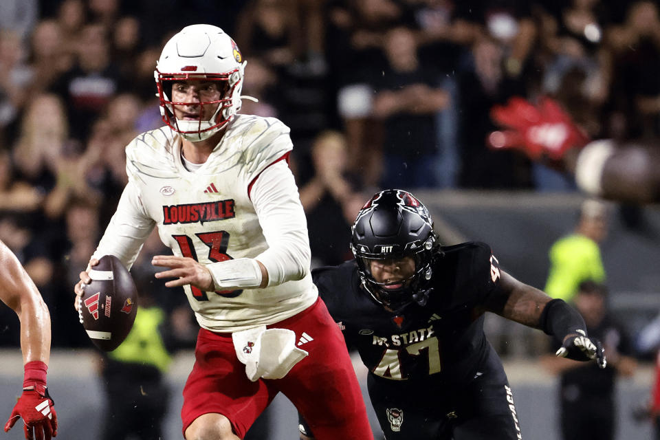 Louisville's Jack Plummer (13) slips away from North Carolina State's Red Hibbler (47) during the second half of an NCAA college football game in Raleigh, N.C., Friday, Sept. 29, 2023. (AP Photo/Karl B DeBlaker)