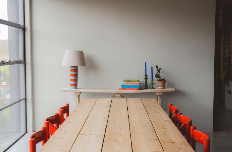 a wooden table with orange chairs around it, and a side table with ujjayi paint colour on the walls