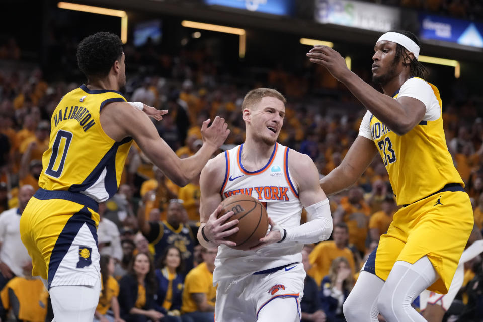 New York Knicks guard Donte DiVincenzo, center, drives between Indiana Pacers guard Tyrese Haliburton, left, and center Myles Turner, right, during the first half of Game 6 in an NBA basketball second-round playoff series, Friday, May 17, 2024, in Indianapolis. (AP Photo/Michael Conroy)
