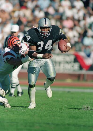 Raiders running back Bo Jackson is seen carrying the ball and running past a Bengals player