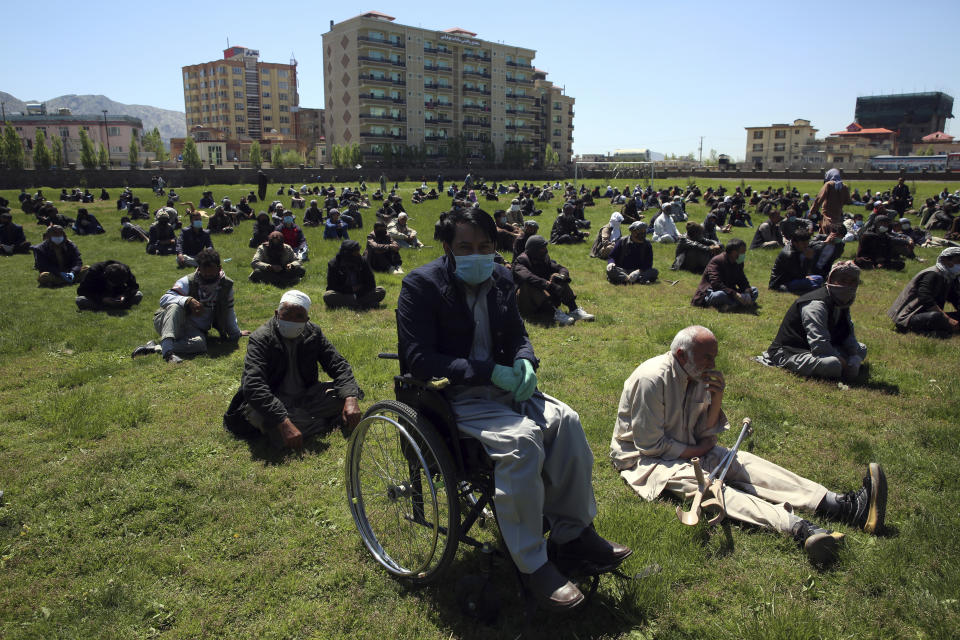 CORRECTS DATE TO TUESDAY, APRIL 21, 2020 -- Afghans wait to receive free wheat donated by the Afghan government ahead of the upcoming holy Muslim fasting month of Ramadan, during a quarantine for the coronavirus, in Kabul, Afghanistan, Tuesday, April 21, 2020. (AP Photo/Rahmat Gul)