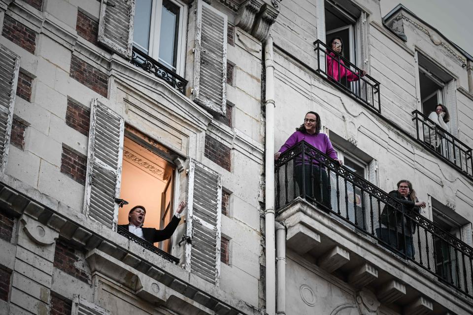 An opera tenor singer performs the song O sole mio from his window in Paris on March 26, 2020 on the evening of the tenth day of a strict lockdown in France aimed at curbing the spread of COVID-19, caused by the novel coronavirus.