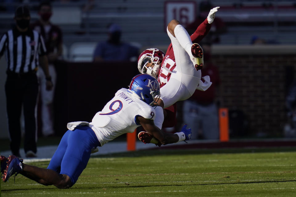 Oklahoma wide receiver Theo Wease (10) is upended by Kansas cornerback Karon Prunty (9) in the first half of an NCAA college football game in Norman, Okla., Saturday, Nov. 7, 2020. (AP Photo/Sue Ogrocki)