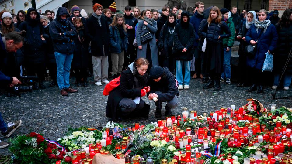 People lay candles outside the university to honor victims of the mass shooting. - Denes Erdos/AP