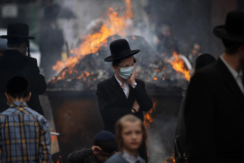 Ultra-Orthodox Jewish men and children, some wearing face mask, burn leavened items in final preparation for the Passover holiday in the ultra-Orthodox Jewish town of Bnei Brak, near Tel Aviv, Israel, Friday, March 26, 2021. Israelis will once again hold large family gatherings this weekend to celebrate Passover, the festive Jewish holiday recalling the biblical flight of the Israelites from Egypt. That's thanks to a highly successful coronavirus vaccination campaign that has inoculated 80% of the country's adult population. (AP Photo/Oded Balilty)