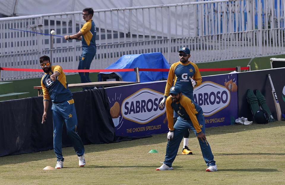 Pakistan players, Imad Wasim, left, throws the ball while teammates Haris Sohail, center front, and Babar Azam watch during a practice session at the Pindi Cricket Stadium, in Rawalpindi, Pakistan, Thursday, Oct. 29, 2020. The Zimbabwe cricket team is in Pakistan to play three ODIs and three Twenty20 International match series, beginning with the first ODI on Friday. (AP Photo/Anjum Naveed)