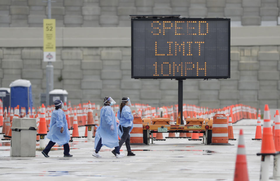 Healthcare workers walk past rows of traffic cones and a speed limit sign, Wednesday, Aug. 5, 2020, at a COVID-19 testing site outside Hard Rock Stadium in Miami Gardens, Fla. State officials say Florida has surpassed 500,000 coronavirus cases. Meanwhile, testing is ramping up following a temporary shutdown of some sites because of Tropical Storm Isaias. (AP Photo/Wilfredo Lee)