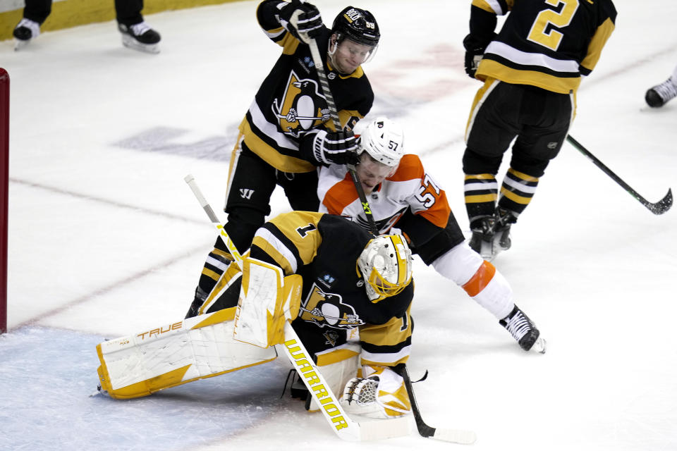 Pittsburgh Penguins goaltender Casey DeSmith (1) smothers the puck as Jake Guentzel helps out defending Philadelphia Flyers' Wade Allison during the first period of an NHL hockey game in Pittsburgh, Sunday, April 2, 2023. (AP Photo/Gene J. Puskar)