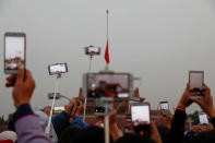 People take pictures as they attend a flag-raising ceremony at Tiananmen Square a day before the 19th National Congress of the Communist Party of China begins in Beijing, China, October 17, 2017. REUTERS/Damir Sagolj