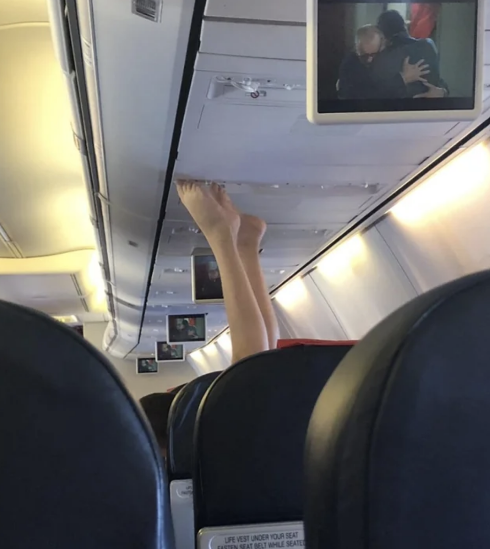 A person's feet touching the ceiling in a plane