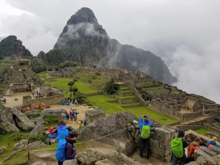 A cloudy morning at Machu Picchu, with tourists taking pictures.