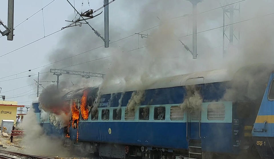 Flames rise from a train set on fire by protestors in Patna, India, Thursday, June 16, 2022. Violence erupted in parts of India on Thursday with thousands of angry youths setting train coaches and vehicles on fire, blocking highways and attacking police with rocks to protest a new short-term government recruitment policy for the military. Under the new job program announced by Defense Minister Rajnath Singh this week, the armed forces this year can recruit 46,000 men and women in the age group 17.5-21 but only for four years. Seventy-five percent of them will be compulsorily retired after four years with no pension benefits. (AP Photo/Sanjay Kumar Srivastava)